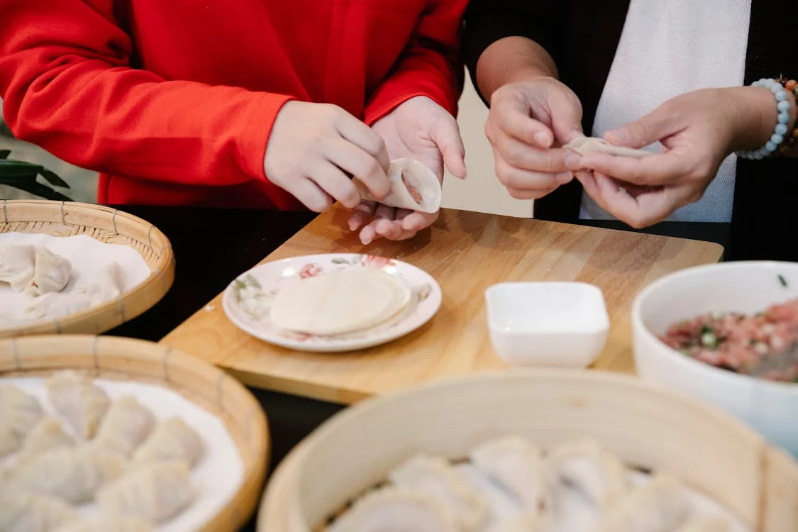 hands folding filling in wrapper to make pork gyoza